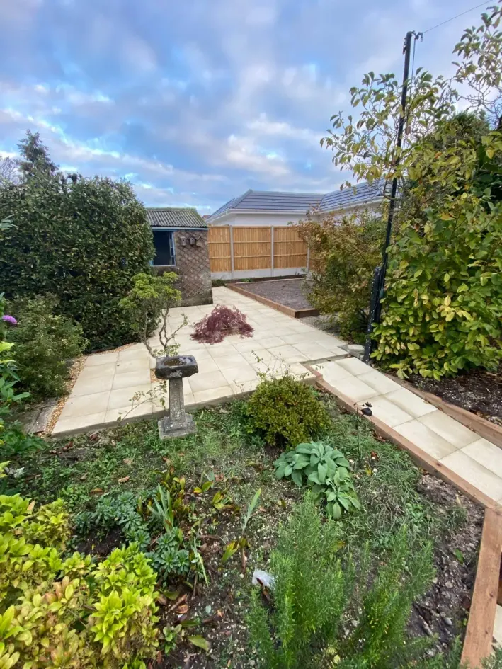 New cream porcelain patio with raised timber-edged beds and planted borders