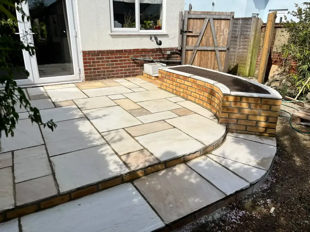 Sandstone patio with curved brick raised planter by the back door