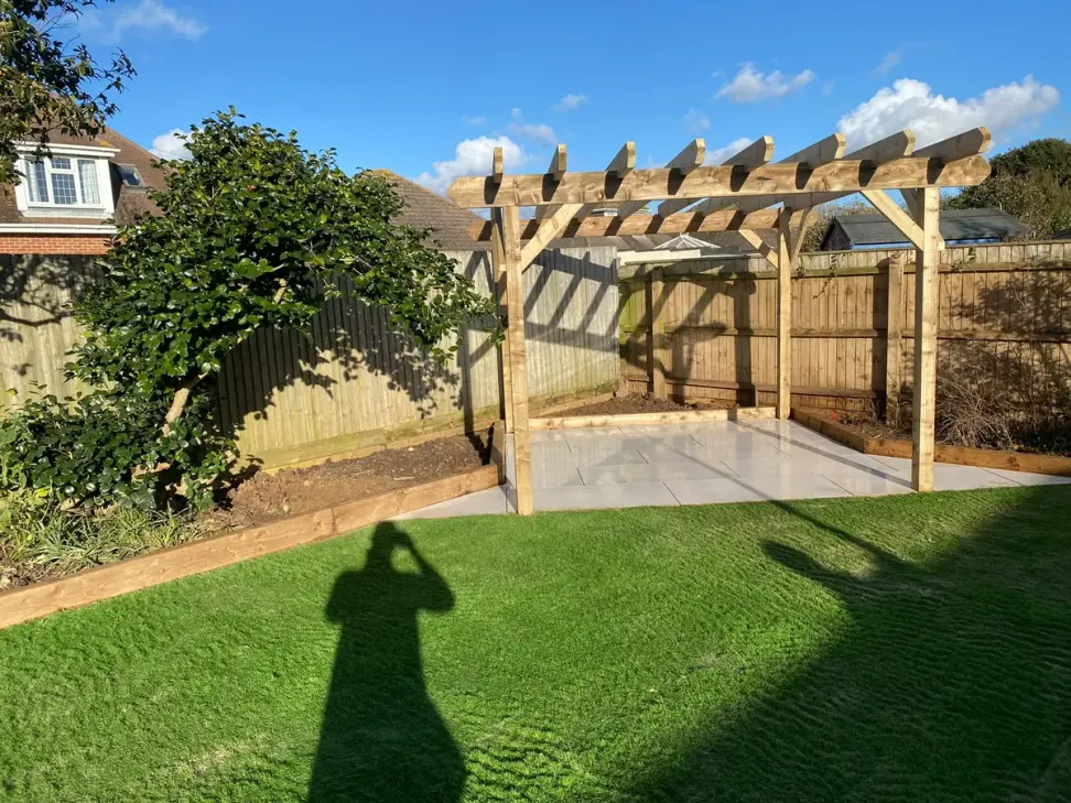 Timber pergola over a patio beside a freshly laid lawn with sleeper edging