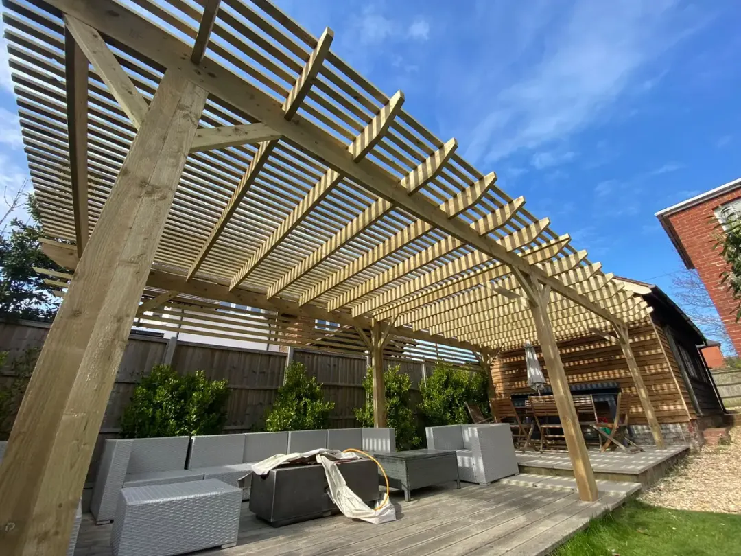 Large timber pergola with slatted roof over an outdoor lounge