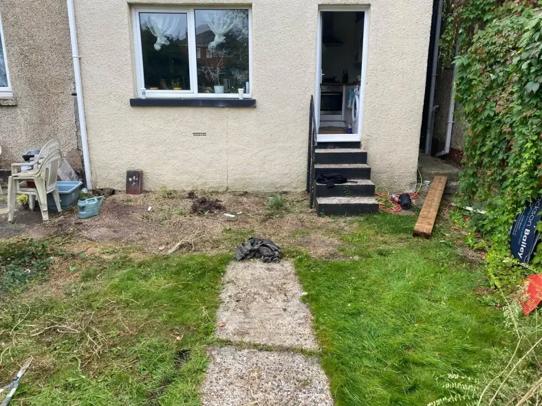 Garden before the work: patchy grass, worn ground and old steps at the back of the house