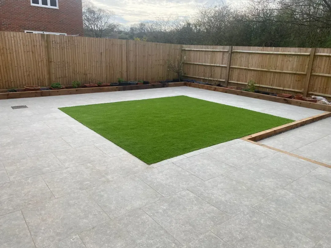 Grey porcelain patio framing a square of artificial grass